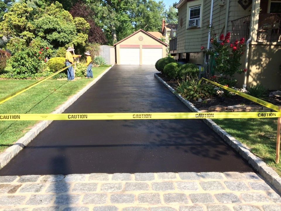 Residential driveway asphalt resurfacing with workers in safety vests